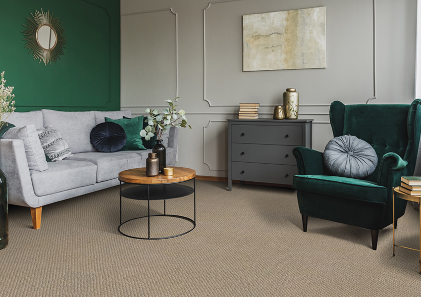 brown carpet in living room with grey couch and green accent chair